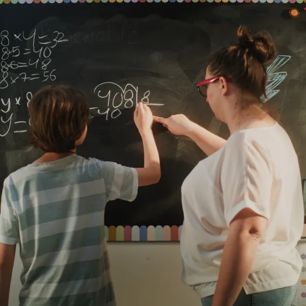 Profesora y alumna haciendo cuentas en la pizarra