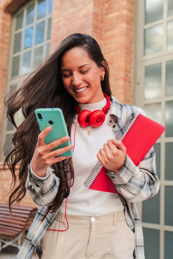 Chica con movil y auriculares sujetando un cuaderno